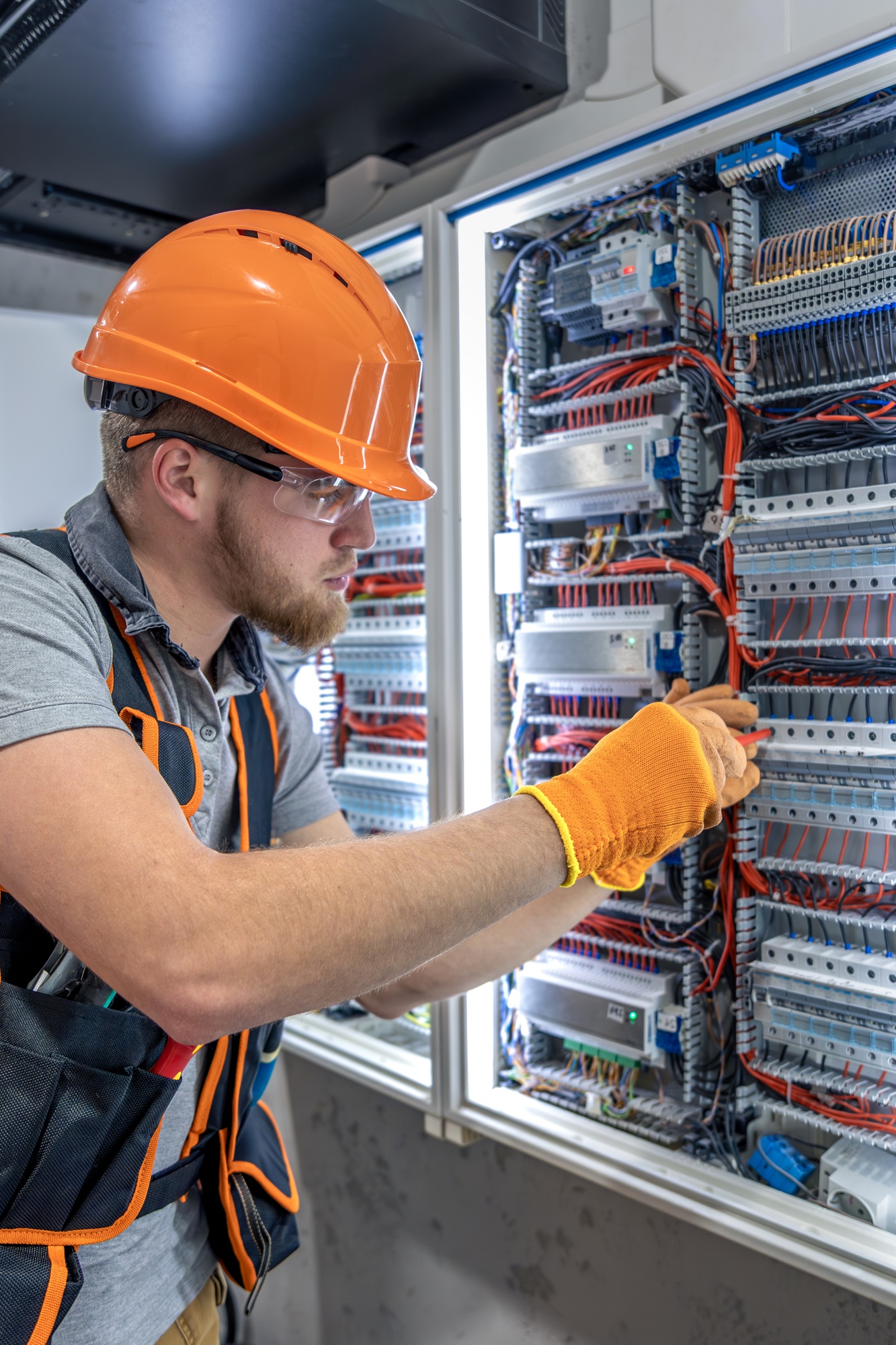 Male electrician working in electrical panel. Male electrician in overalls.